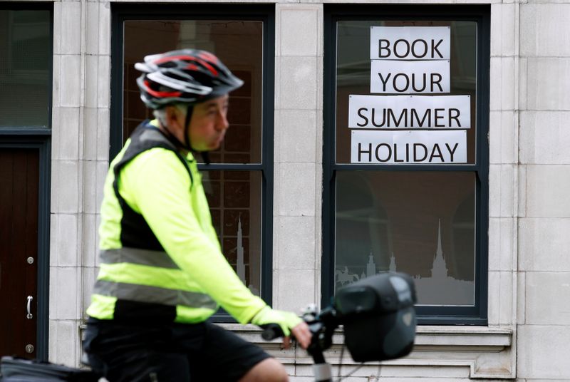 &copy; Reuters. Man rides a bicycle past a travel agents store, in Manchester