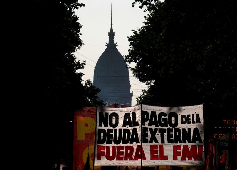 &copy; Reuters. Foto de archivo: manifestantes sostienen carteles en contra del pago de la deuda en una marcha en Buenos Aires