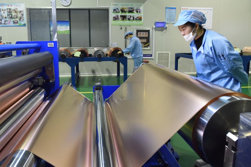 © Reuters. Workers are seen at a production line of copper foils used for lithium batteries, at a Tongling Nonferrous Metals Group plant