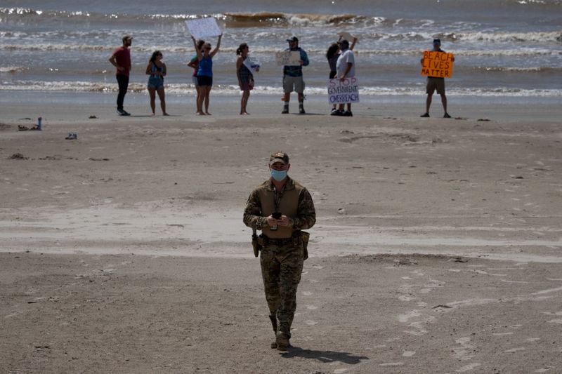 &copy; Reuters. Policeman walks away from residents protesting closed beaches on 4th of July amid the global outbreak of the coronavirus disease in Galveston, Texas