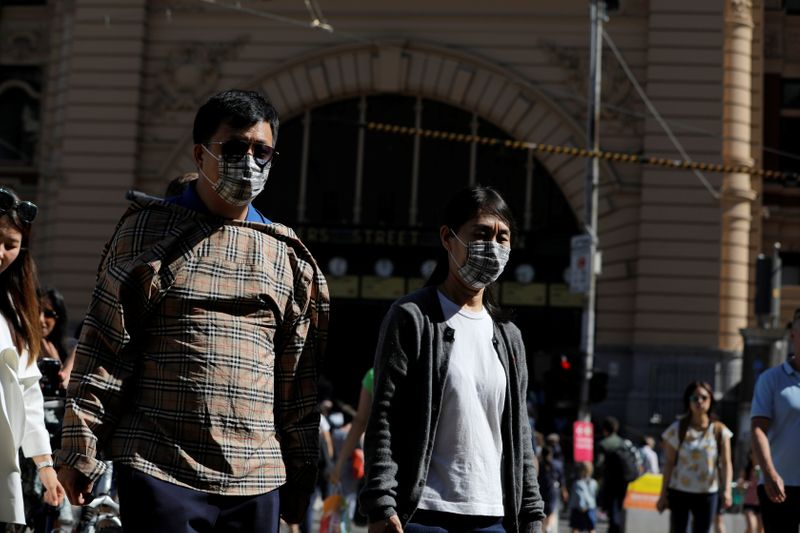 &copy; Reuters. Delle persone con indosso la mascherina vicino alla stazione di Flinders Street dopo la notizia di nuovi casi di coronavirus a Melbourne, stato della Victoria, Australia