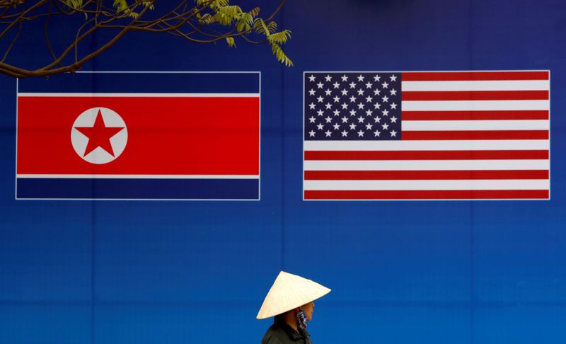 © Reuters. A person walks past a banner showing North Korean and U.S. flags ahead of the North Korea-U.S. summit in Hanoi