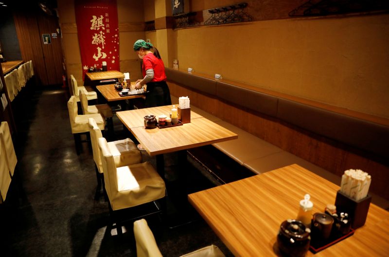 &copy; Reuters. FILE PHOTO: A waitress wearing a protective mask cleans a table at Toshirhin restaurant in Tokyo
