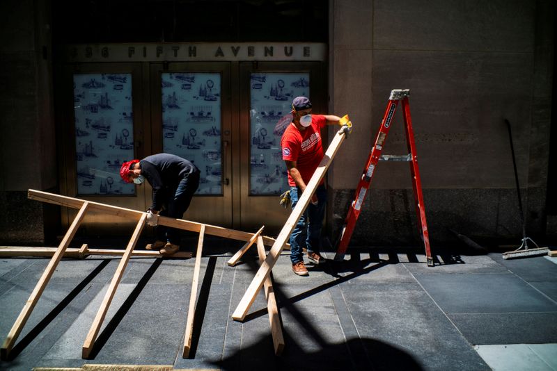 &copy; Reuters. FILE PHOTO: Workers remove boards from windows in a local store, as phase one of reopening after lockdown begins, during the outbreak of the coronavirus disease (COVID-19), at 5th Avenue in New York City