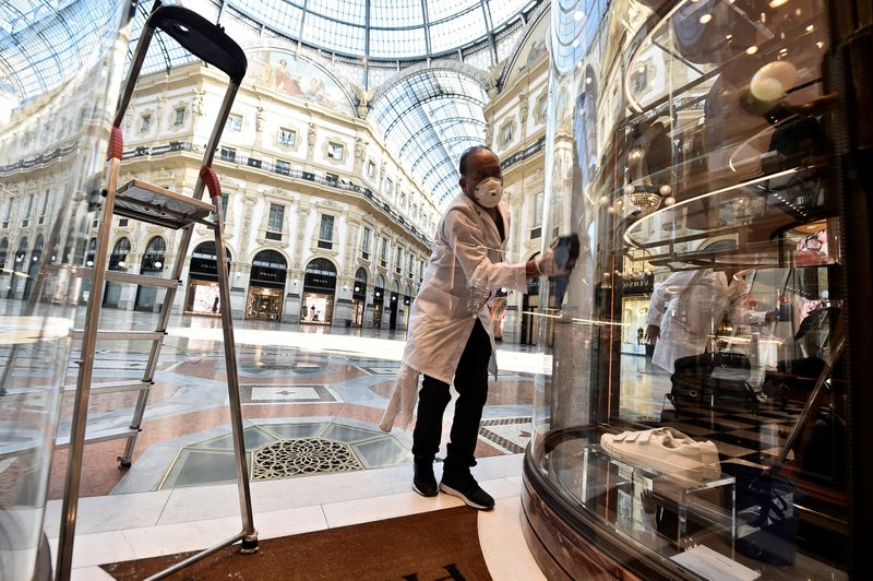 &copy; Reuters. Un impiegato disinfetta la vetrina di un negozio nella Galleria Vittorio Emanuele II a Milano