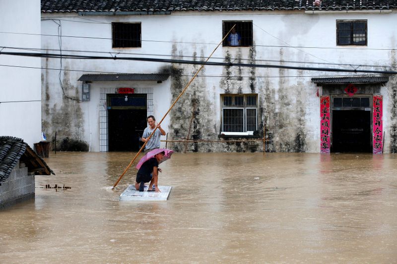 &copy; Reuters. Personas sobre una balsa improvisada durante inundaciones tras fuertes lluvias en Huangshan