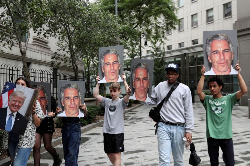 © Reuters. FILE PHOTO: Demonstrators hold photos aloft protesting Jeffrey Epstein in New York