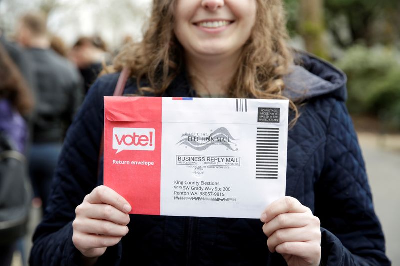 © Reuters. FILE PHOTO: Lexi Menth of Seattle holds up her vote-by-mail ballot as supporters line up at a rally for U.S. Democratic 2020 presidential candidate Senator Elizabeth Warren at the Seattle Center Armory in Seattle