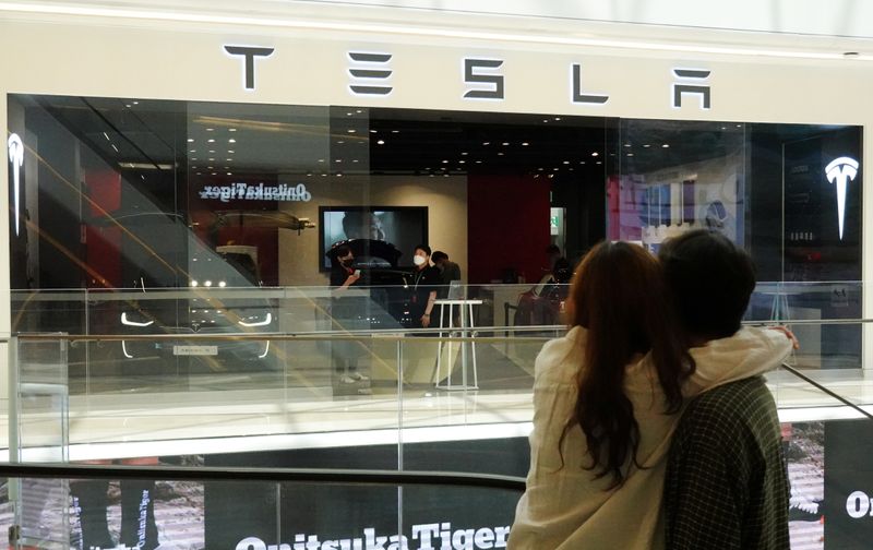 &copy; Reuters. A couple looks at a Tesla dealership in Hanam