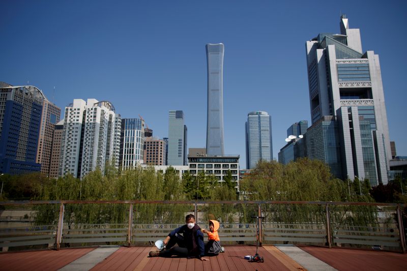 &copy; Reuters. FILE PHOTO: A man and a child sit in a park near the Central Business District on a “blue sky day&quot; in Beijing as the spread of the novel coronavirus disease (COVID-19) continues