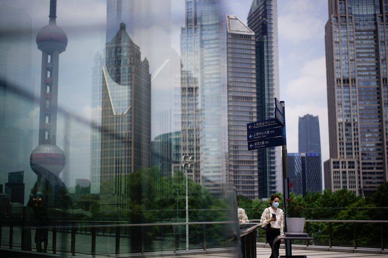 &copy; Reuters. Прохожий в защитной маске в финансовом районе Шанхая