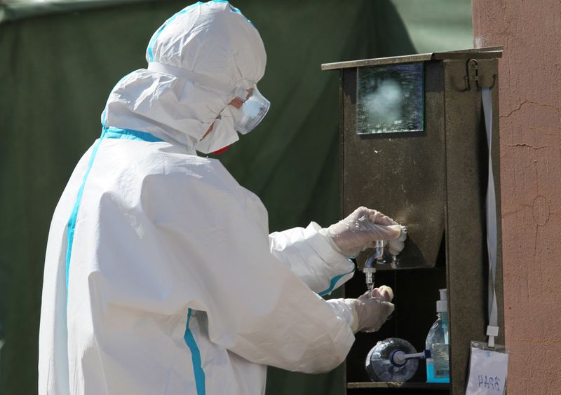 &copy; Reuters. Медицинский работник в защитном костюме моет руки у дневного стационара для лечения зараженных коронавирусом в Бишкеке