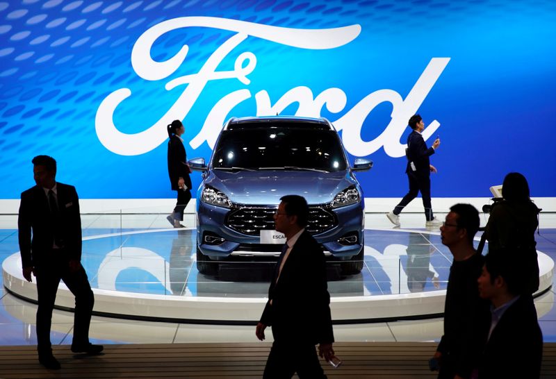 &copy; Reuters. FILE PHOTO: People walk by a Ford Escape SUV displayed during the media day for the Shanghai auto show in Shanghai