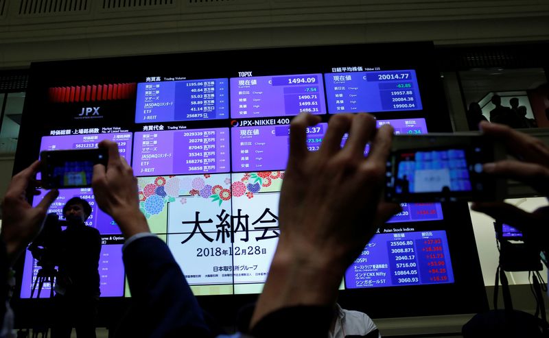 &copy; Reuters. FILE PHOTO: Attendees take pictures of a stock quotation board after a ceremony marking the end of trading in 2018 at the Tokyo Stock Exchange (TSE) in Tokyo