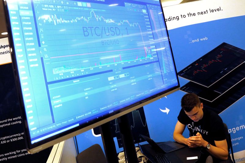 &copy; Reuters. FILE PHOTO: A man works beneath a display showing the market price of Bitcoin on the floor of the Consensus 2018 blockchain technology conference in New York City
