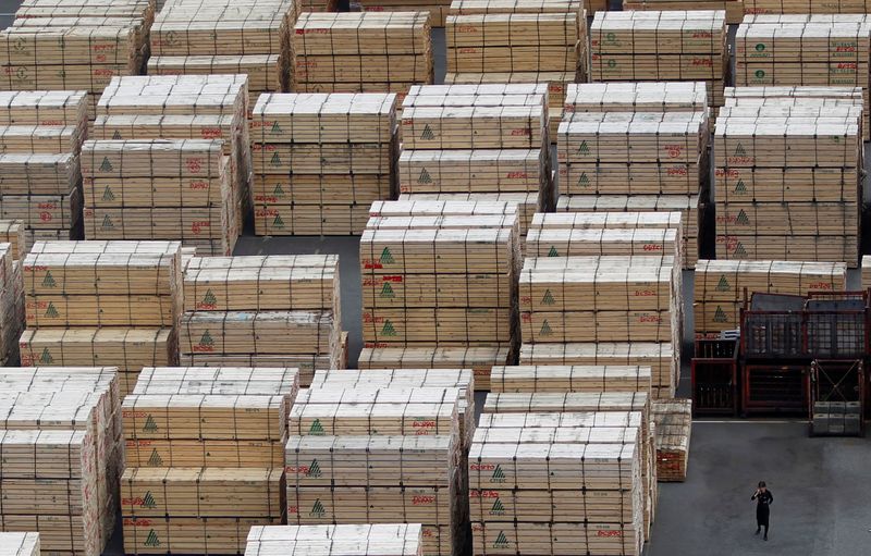 &copy; Reuters. Woman using mobile phone stands in front of piles of woods at Keihin industrial zone in Kawasaki, south of Tokyo