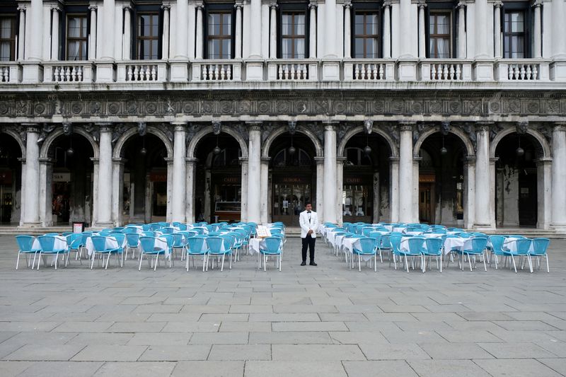 © Reuters. FILE PHOTO: A waiter stands by empty tables outside a restaurant at St Mark's Square, which is usually full of tourists, after Italy's government adopted a decree with emergency new measures to contain the coronavirus, in Venice