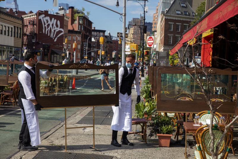 &copy; Reuters. FILE PHOTO: Waiters at a restaurant adjust social distancing screens outside for outdoor seating a restaurant in New York City
