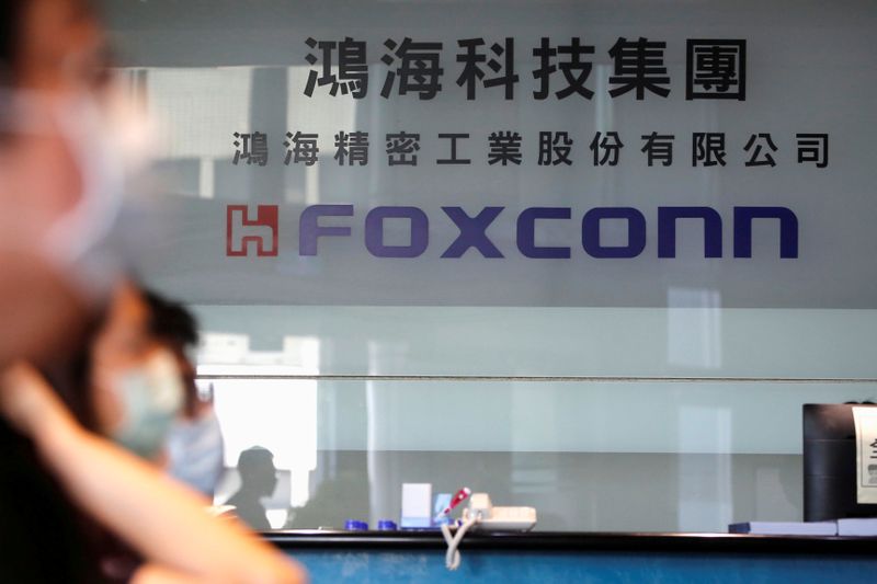 &copy; Reuters. FILE PHOTO: People wear masks to protect themselves from coronavirus disease (COVID-19), while listening to the annual general meeting at the lobby of Foxconn&apos;s office in Taipei