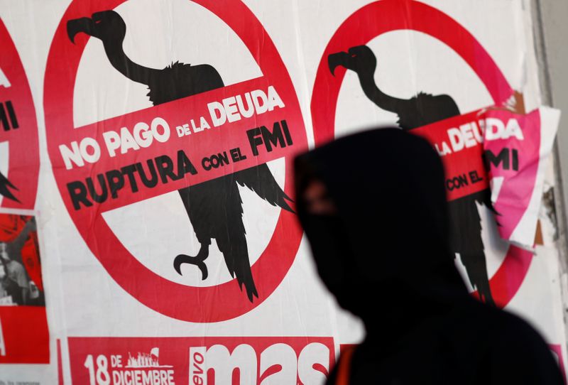 &copy; Reuters. A pedestrian wearing a face mask walks past posters on the street that read &quot;No to the payment of the debt. Break with the IMF&quot;, in Buenos Aires