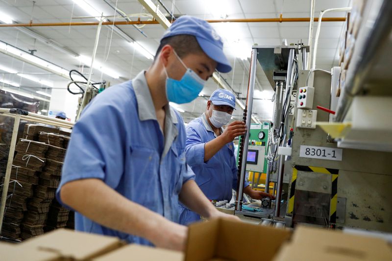 &copy; Reuters. FILE PHOTO: Employees wearing masks work at a factory of the component maker SMC during a government organised tour of its facility following the outbreak of the coronavirus disease (COVID-19), in Beijing