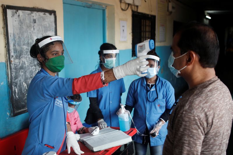 &copy; Reuters. Funcionária de equipe médica mede temperatura de homem em escola em Mumbai, na Índia