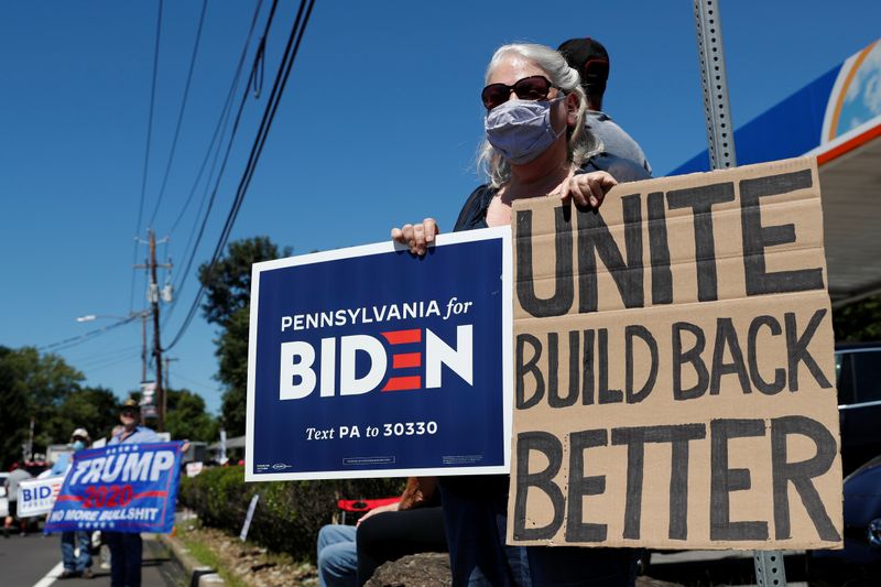 &copy; Reuters. Mulher com cartazes de apoio a Joe Biden ao lado de apoiadores do presidente dos EUA, Donald Trump, em Old Forge, na Pensilvânia