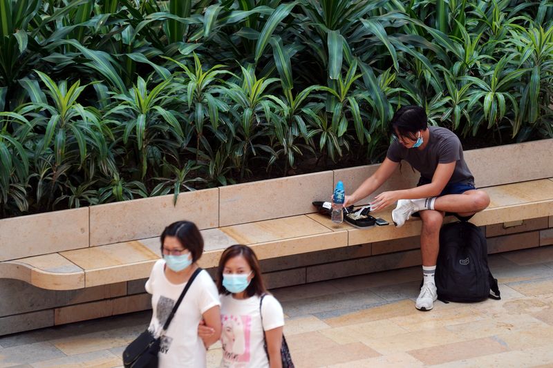 &copy; Reuters. FILE PHOTO: Women walk past a man eating takeaway food inside a shopping mall in Hong Kong