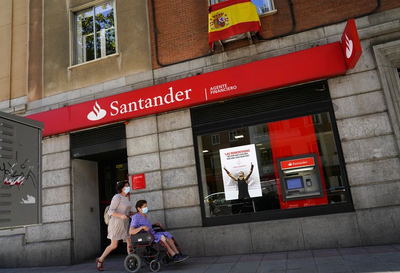 &copy; Reuters. FOTO DE ARCHIVO. Mujeres con mascarillas caminan frente a una sucursal de Banco Santander, en Madrid, España