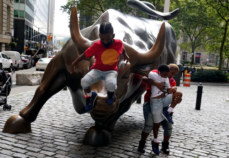 &copy; Reuters. Criança brinca em cima e estátua e touro localizada em frente à Bolsa de Valores de Nova York