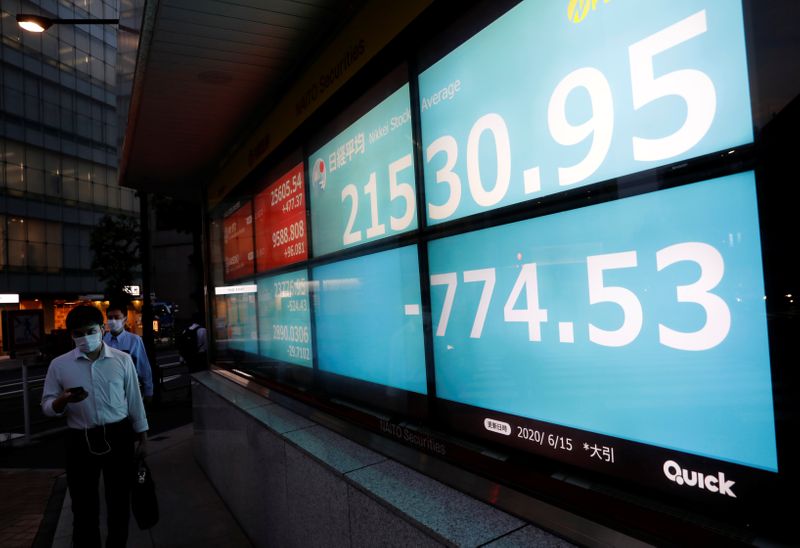 &copy; Reuters. FILE PHOTO: Men wearing protective face masks, following the coronavirus disease (COVID-19) outbreak, walk past a stock quotation board outside a brokerage in Tokyo