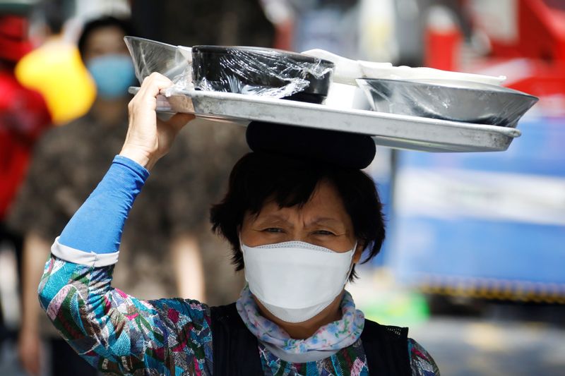 &copy; Reuters. A restaurant worker carring a meal on her head walks on Myeongdong shopping district which is nearly empty amid the coronavirus disease (COVID-19) pandemic in Seoul