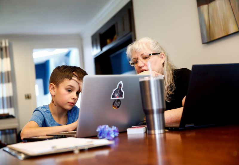 © Reuters. FILE PHOTO: Caidence Miller, a 4th grader at Cottage Lake Elementary, works with his grandmother Chrissy Brackett as they try to figure out how to navigate an online learning system.