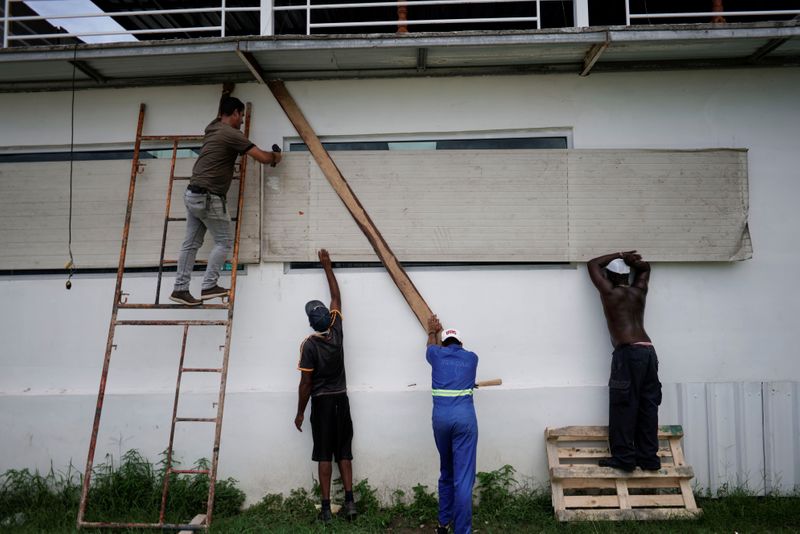 © Reuters. Workers protect the windows of a bar in anticipation of the Tropical Storm Laura arrival, in Havana