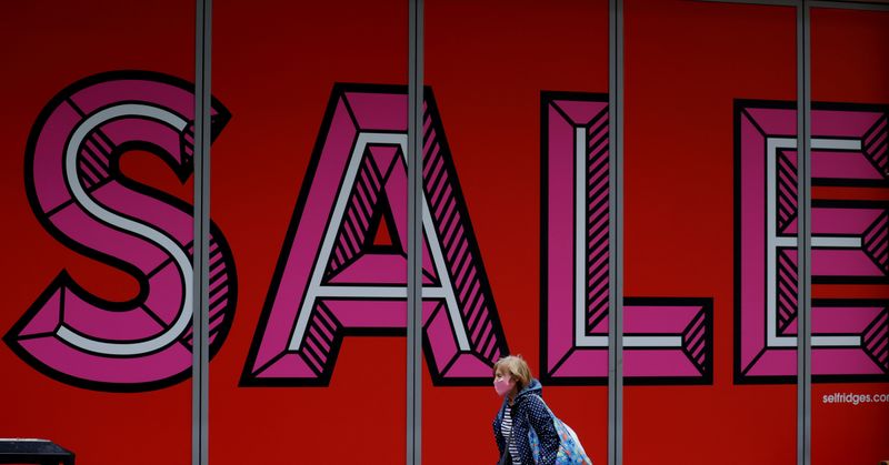 &copy; Reuters. FILE PHOTO: A woman wearing a protective face covering walks past a sale sign in a shop window following the outbreak of the coronavirus disease (COVID-19), in Manchester, Britain