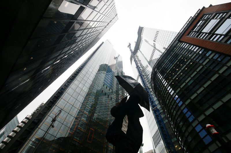 © Reuters. FILE PHOTO: A person walks through the financial district during rainy weather in London