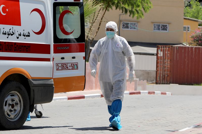 &copy; Reuters. Agente de saúde palestino caminha em direção a ambulância após morte de idoso por Covid-19 em Gaza