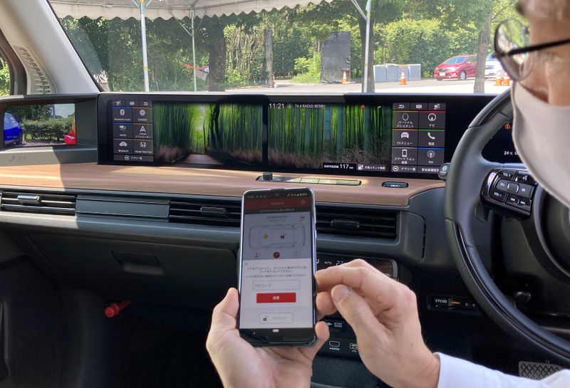 &copy; Reuters. An employee of Honda Motor demonstrates a digital key app on a smartphone inside a Honda E electric car in Haga Town