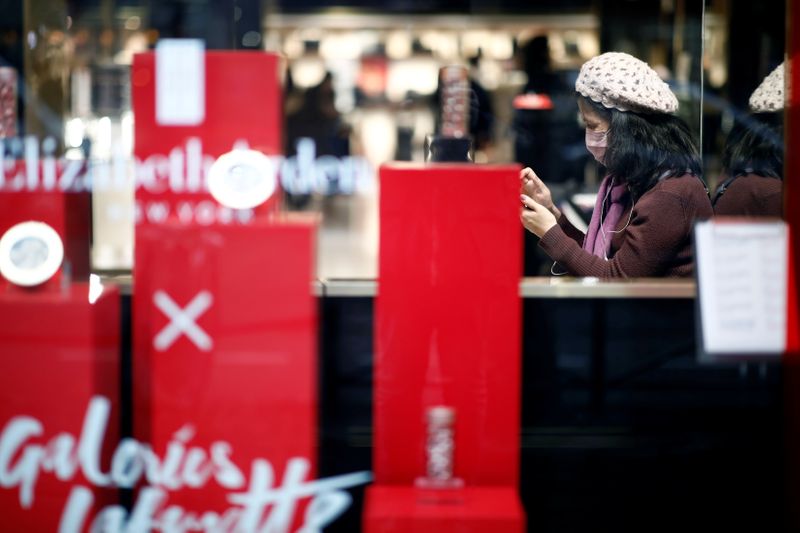 &copy; Reuters. Tourist wears a protective mask as she looks at her mobile phone at the Galeries Lafayette department store in Paris as the country is hit by the new coronavirus