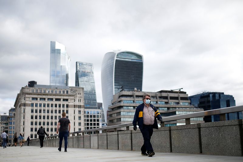 © Reuters. The financial district can be seen as a man wearing a protective face mask walks over London Bridge, amid the coronavirus disease (COVID-19) outbreak, in London