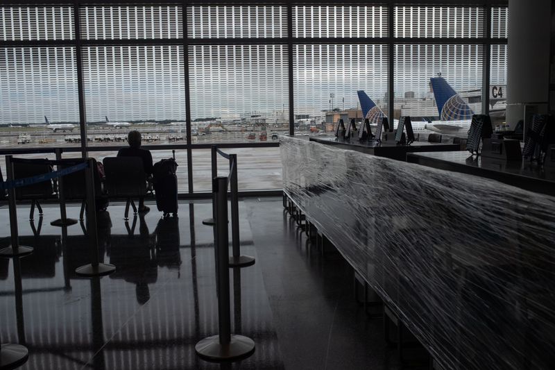 © Reuters. United Airlines planes are seen in background as a lone traveler awaits next to a closed restaurant at IAH airport in Houston