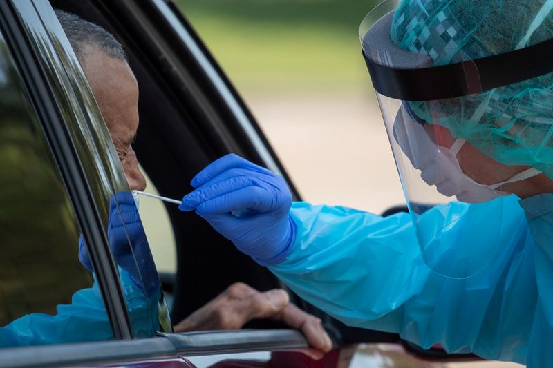 &copy; Reuters. FILE PHOTO: Health care worker uses a swab to test man at COVID-19 drive in testing location in Houston, Texas