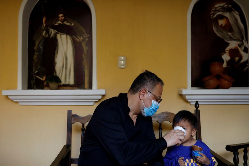 © Reuters. FILE PHOTO: Fray Carlos Caceres gives a beverage to an unaccompanied child who was deported from the U.S., at a shelter in Guatemala City