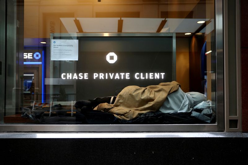 &copy; Reuters. FILE PHOTO: A homeless man sleeps in a closed Chase bank branch on a nearly deserted Wall Street in Manhattan, in New York