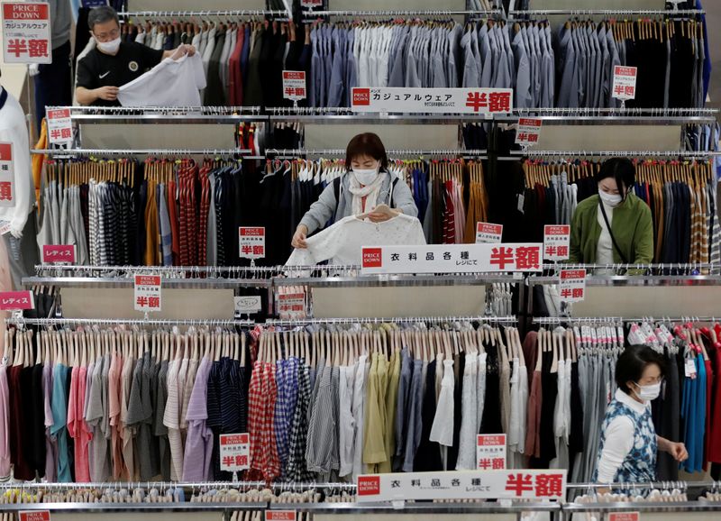 © Reuters. FILE PHOTO: Shoppers wearing protective masks choose clothes at Japan's supermarket group Aeon's shopping mall as the mall reopens amid the coronavirus disease (COVID-19) outbreak in Chiba