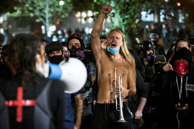 © Reuters. A man holding a trumpet gestures against supporters of U.S. President Donald Trump who drove in a caravan in Portland