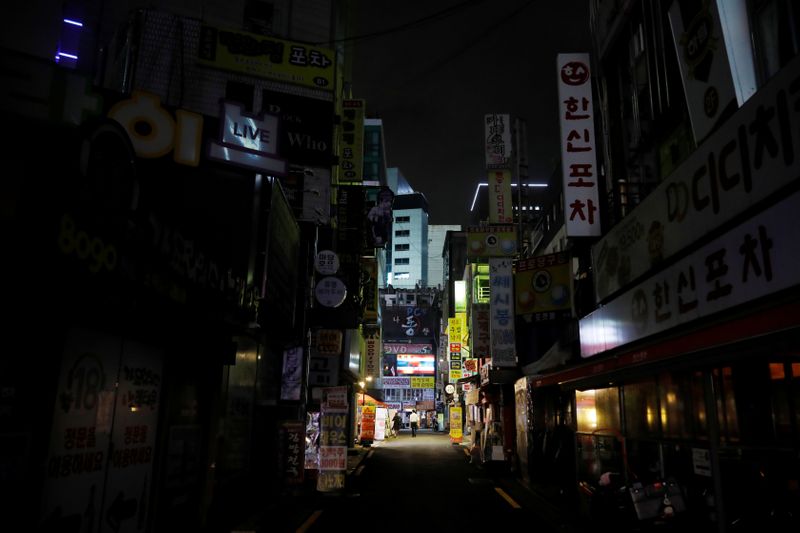 &copy; Reuters. People walk past closed pubs and restaurants as tougher social distancing rules to prevent the coronavirus disease (COVID-19) that have been announced on the last Friday continue, in Seoul