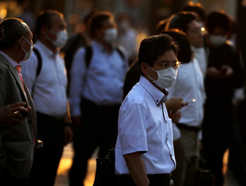 &copy; Reuters. FILE PHOTO: Office workers wearing protective face masks walk to head home at sunset amid the coronavirus disease (COVID-19) outbreak, in Tokyo