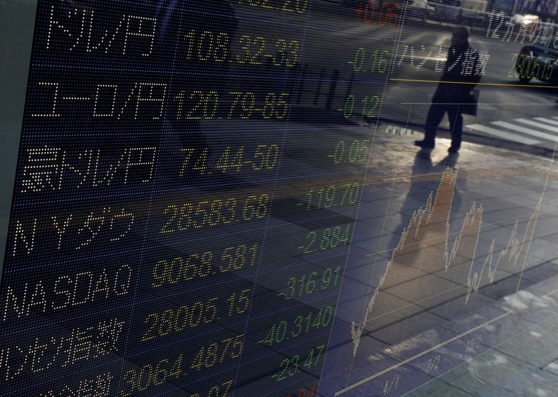 &copy; Reuters. Un passante riflesso su un cartellone elettronico su cui sono riflesse informazioni di borsa presso la Tokyo Stock Exchange, 8 gennaio 2020