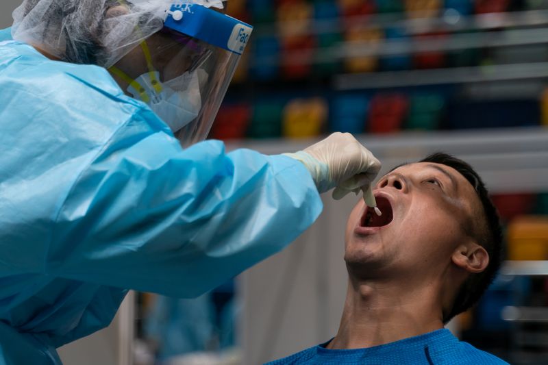 © Reuters. Swab sample is collected from a man by medical staff at the community testing centre for the coronavirus disease (COVID-19) in Hong Kong